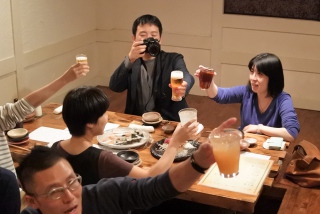 写真：懇親会の乾杯の様子。後藤さんはカメラを構えながらビールを掲げている