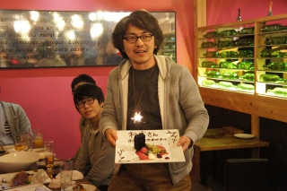 写真：サプライズのケーキを掲げる杉本さん