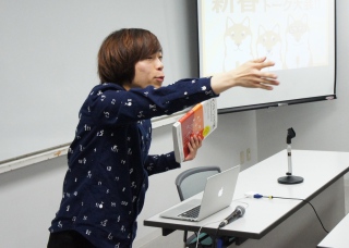 写真：書籍を手に参加者に話しかける坂上さん